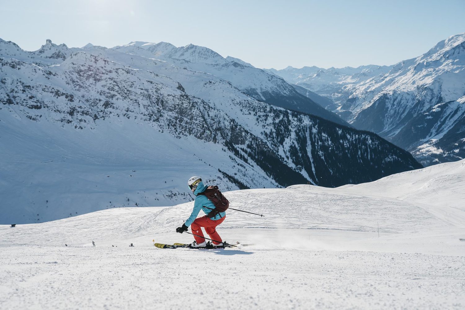 Narciarz zjeżdżający po szerokim stoku w otoczeniu wysokich, ośnieżonych gór we francuskim Serre Chevalier – zimowy wypoczynek z biurem podróży promoclub.pl