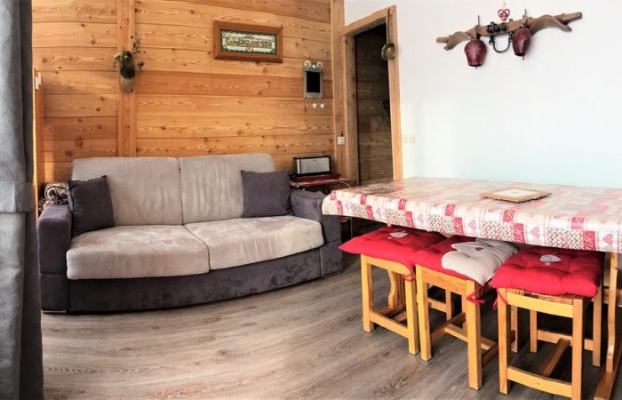 Przytulny salon w apartamencie w Les Sybelles, La Toussuire – drewniane wnętrze z sofą i stołem jadalnym, idealne zakwaterowanie na narty we Francji – promoclub.pl