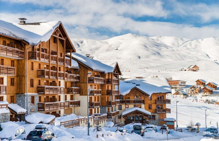 Urokliwy alpejski resort położony tuż przy stokach narciarskich — drewniane budynki w stylu chalet doskonale komponują się z otaczającym krajobrazem górskim, tworząc idealne miejsce na zimowy wypoczynek