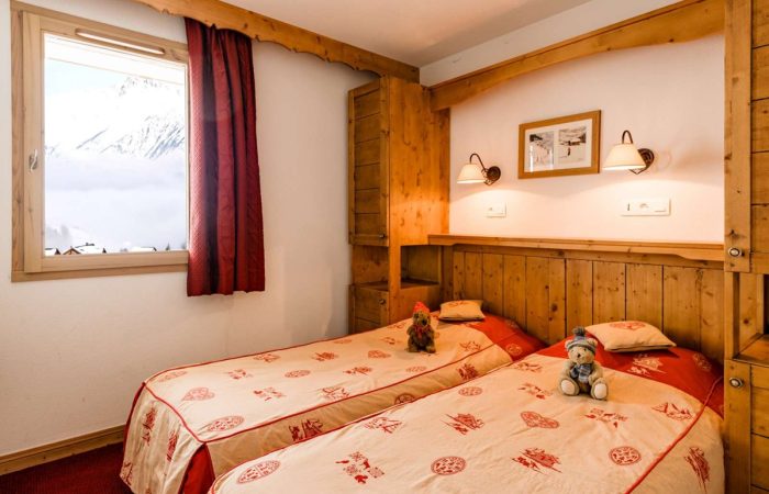 Przytulna sypialnia w górskim stylu – ciepłe drewno, miękka pościel i widok na ośnieżone szczyty tworzą idealne warunki do wypoczynku po dniu pełnym zimowych atrakcji